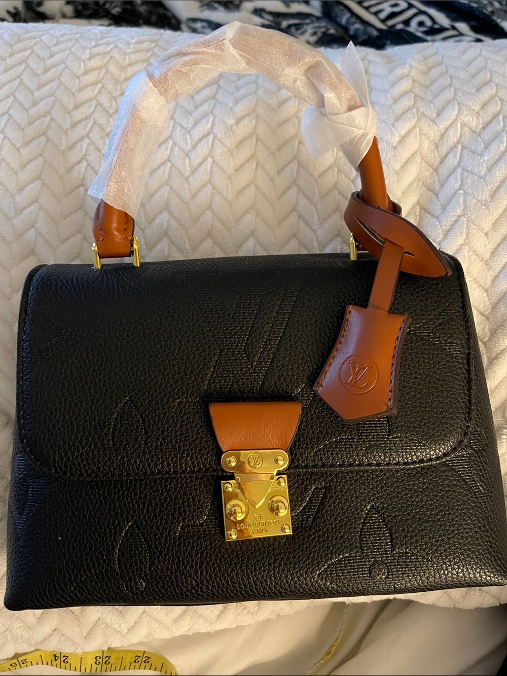 Black embossed satchel with brown trim. Has crossbody strap.